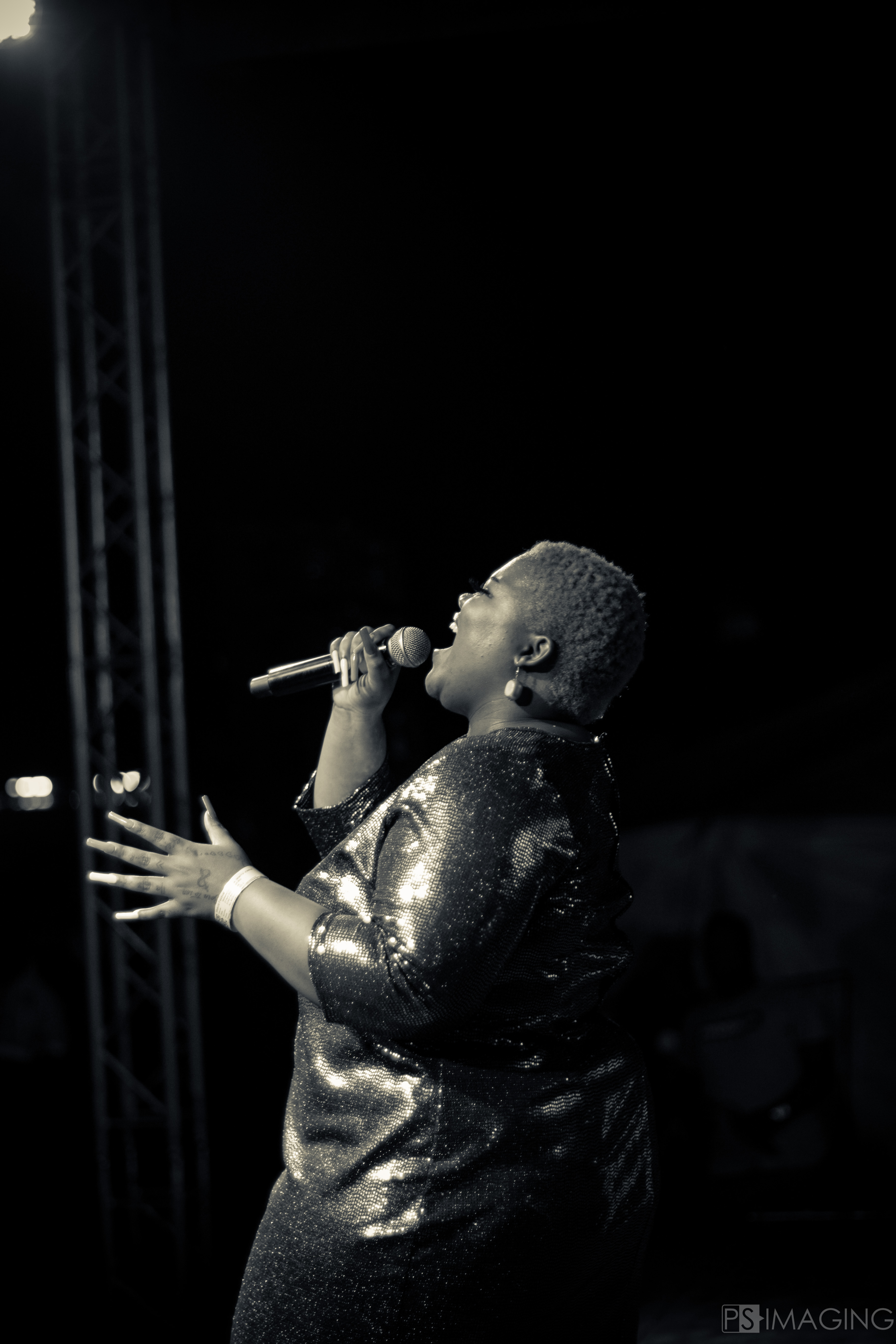 man watching a band on the stage wearing a red t-shirt and black hat.